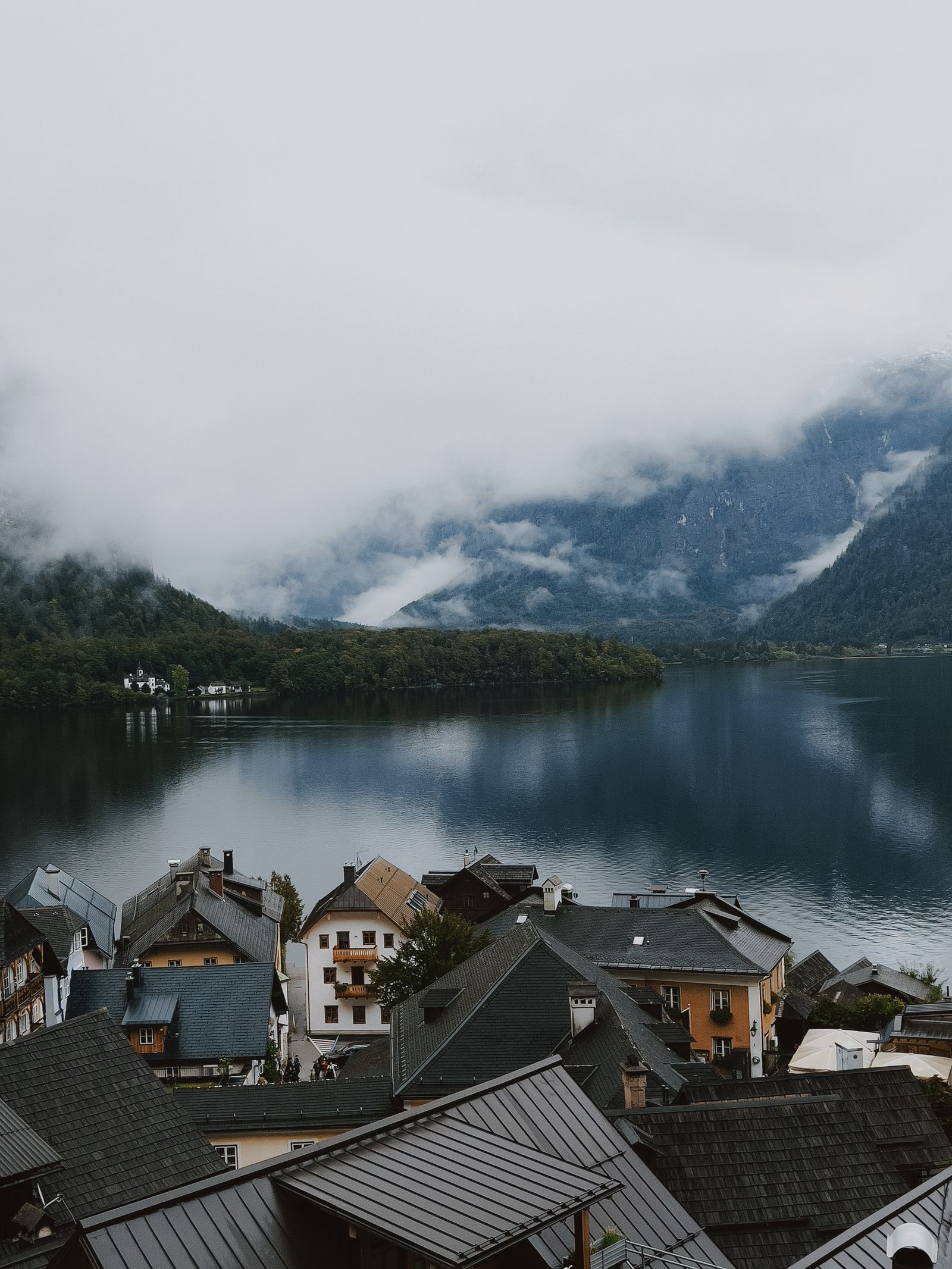 Nebelverhangener See mit Dorf in den Alpen